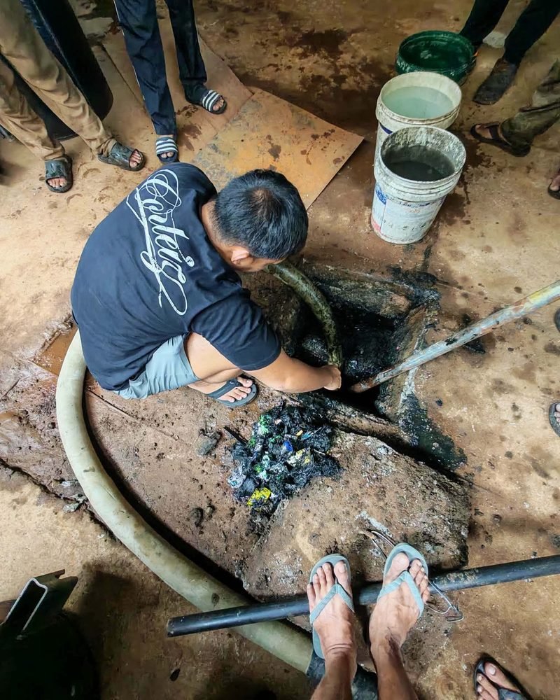 Technician manually clearing a clogged drain